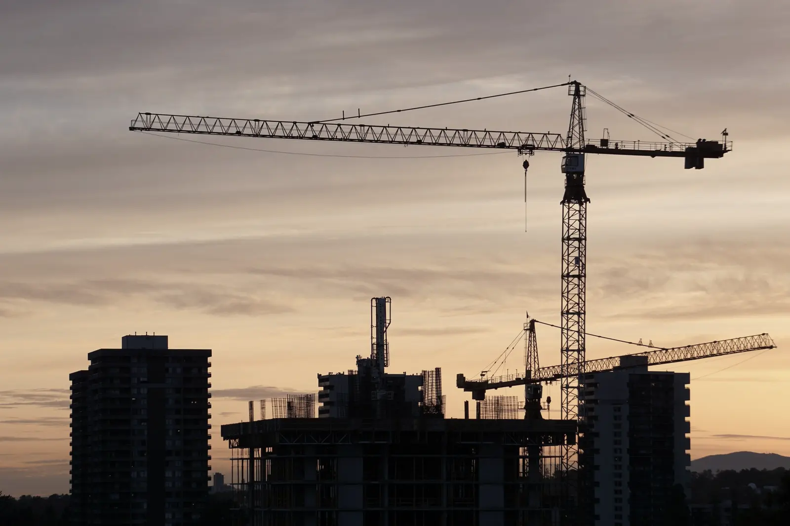 Grues à tour et bâtiment en construction au coucher du soleil