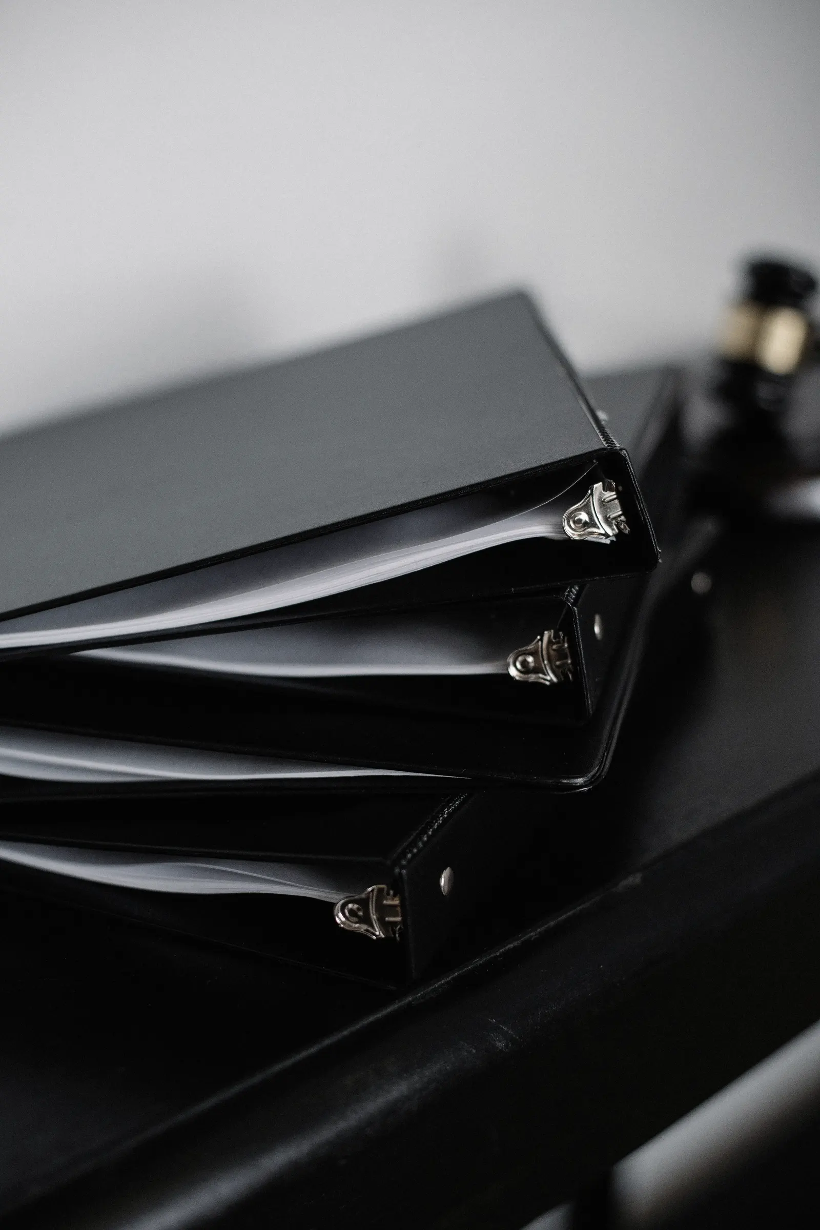 Pile de classeurs noirs contenant des documents sur un bureau